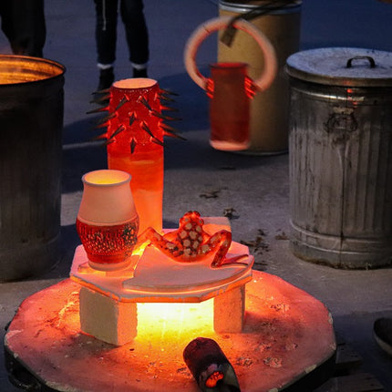 Pieces get moved from the kiln base to nearby metal garbage cans with reduction materials inside.

PHOTO CREDIT: Ella Spillman